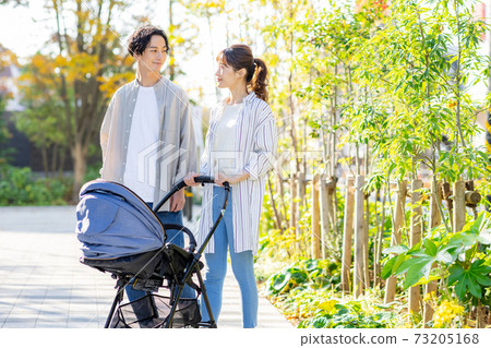 A couple walking outside while holding a baby 73205168