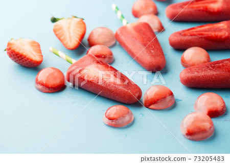 Delicious homemade strawberry popsicles with colorful sticks on blue backgound. Delicious homemade strawberry popsicles with colorful sticks on blue backgound. 73205483
