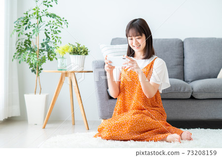 A young woman watching a video on her smartphone A young woman watching a video on her smartphone 73208159