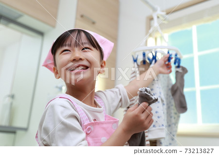 A 5-year-old girl helping to dry the clothes 73213827