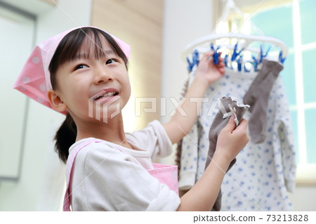 A 5-year-old girl helping to dry the clothes 73213828