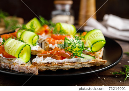 Toasts with salted salmon fish, ricotta cheese, fresh cucumber and ciabatta bread Toasts with salted salmon fish, ricotta cheese, fresh cucumber and ciabatta bread 73214001