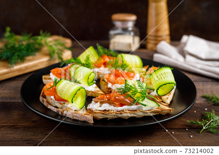 Toasts with salted salmon fish, ricotta cheese, fresh cucumber and ciabatta bread Toasts with salted salmon fish, ricotta cheese, fresh cucumber and ciabatta bread 73214002