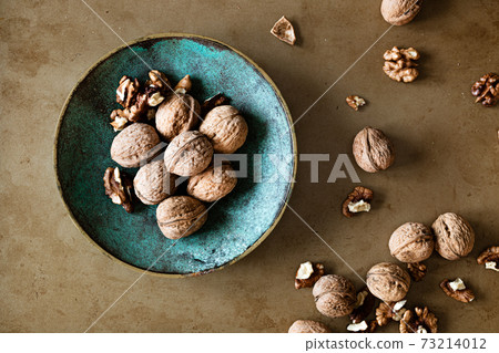 Walnuts in a bowl on a table, overhead view 73214012