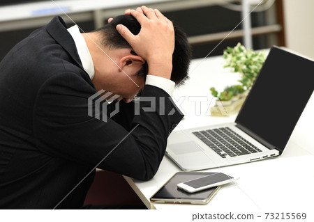 一個男商人抱著他的頭和擔心的形象 73215569