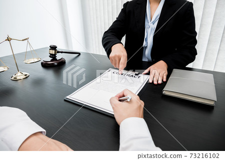 A woman lawyer or a judge counseling clients about judicial justice and prosecution with scales, judges gavel, legal documents legal services concept 73216102
