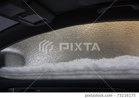 Snow on frozen glass of a car window on frosty winter 73216175