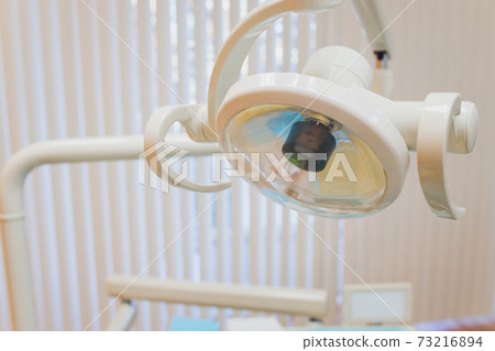 The hand of the dentist with a light. The hand of the dentist with a light. 73216894
