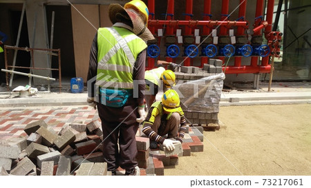 SEREMBAN, MALAYSIA -JULY 06, 2017: Construction workers installing and arranging precast concrete pavers stone for the road at the construction site.  73217061
