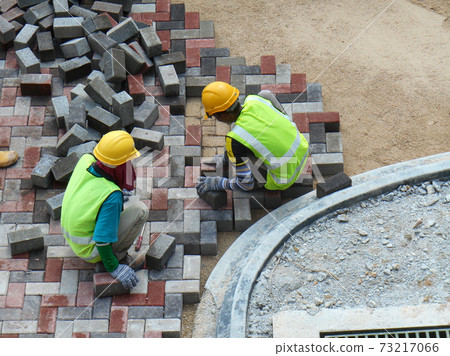 SEREMBAN, MALAYSIA -JULY 06, 2017: Construction workers installing and arranging precast concrete pavers stone for the road at the construction site.  73217066