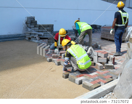 SEREMBAN, MALAYSIA -JULY 06, 2017: Construction workers installing and arranging precast concrete pavers stone for the road at the construction site.  73217072