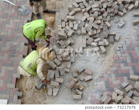 SEREMBAN, MALAYSIA -JULY 06, 2017: Construction workers installing and arranging precast concrete pavers stone for the road at the construction site.  73217076