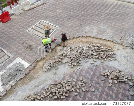 SEREMBAN, MALAYSIA -JULY 06, 2017: Construction workers installing and arranging precast concrete pavers stone for the road at the construction site. SEREMBAN, MALAYSIA -JULY 06, 2017: Construction workers installing and arranging precast concrete pavers stone for the road at the construction site. 73217077