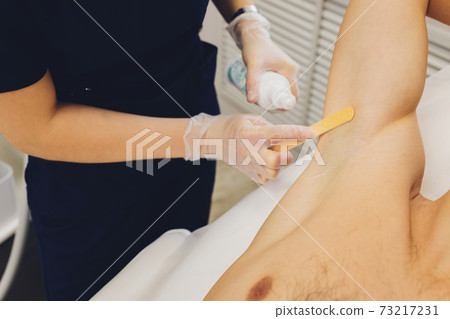 man receiving laser epilation at armpit on beauty center. man receiving laser epilation at armpit on beauty center. 73217231