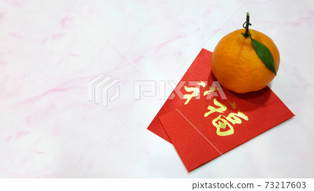 A mandarin orange with red ang pow (a monetary gift given during special occasions in Chinese culture, especially Chinese New Year). On the red angpow (red packet) is the chinese character 'fu'. A mandarin orange with red ang pow (a monetary gift given during special occasions in Chinese culture, especially Chinese New Year). On the red angpow (red packet) is the chinese character 'fu'. 73217603