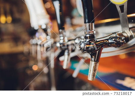 The bar counter with bottles and apparatus for dispensing beer. Apparatus for dispensing beer at the bar. Pub. restaurant. 73218017