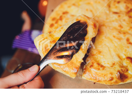 Azerbaijani restaurant dish with vegetable decor on a wooden background. Khachapuri in Megrelian on the Board. Azerbaijani restaurant dish with vegetable decor on a wooden background. Khachapuri in Megrelian on the Board. 73218437