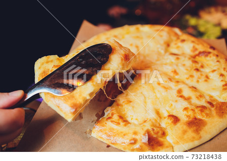 Azerbaijani restaurant dish with vegetable decor on a wooden background. Khachapuri in Megrelian on the Board. Azerbaijani restaurant dish with vegetable decor on a wooden background. Khachapuri in Megrelian on the Board. 73218438
