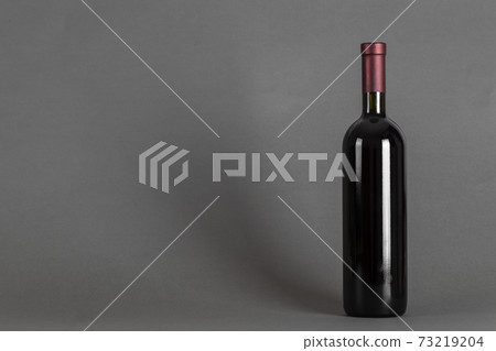 Closed bottle of wine on a grey background. Wine drinking culture concept. Closed bottle of wine on a grey background. Wine drinking culture concept. 73219204