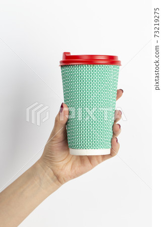 Female hand holding disposable coffee cup green colour on white background. 73219275