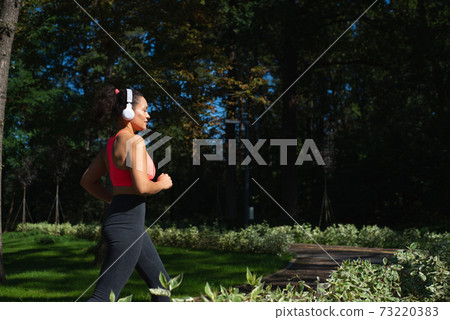 Sunset in the end of the road. Sporty woman runner running outdoor 73220383