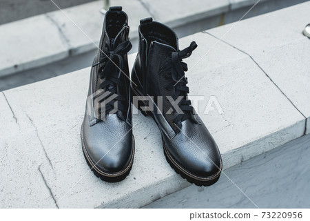 High women's or unisex shoes. Pair of boots with shoe laces. Modern youth fashion of women's casual footwear. Dark grey glossy leather shoes. High women's or unisex shoes. Pair of boots with shoe laces. Modern youth fashion of women's casual footwear. Dark grey glossy leather shoes. 73220956