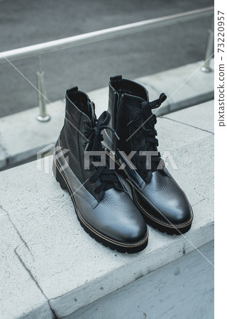 High women's or unisex shoes. Pair of boots with shoe laces. Modern youth fashion of women's casual footwear. Dark grey glossy leather shoes. High women's or unisex shoes. Pair of boots with shoe laces. Modern youth fashion of women's casual footwear. Dark grey glossy leather shoes. 73220957