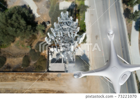 Unmanned Aircraft Drone Flying Near and Inspecting Cell Tower Unmanned Aircraft Drone Flying Near and Inspecting Cell Tower 73221070