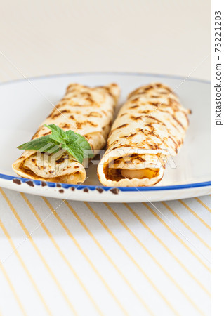 thin pancakes rolled crepes mint on a plate with knife and fork 73221203
