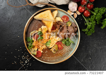 Omelet with beef, avocado and cherry tomatoes. The hot main course for breakfast is made from halal chicken eggs, vegetables and herbs. Classic breakfast with toasted toast. Omelet with beef, avocado and cherry tomatoes. The hot main course for breakfast is made from halal chicken eggs, vegetables and herbs. Classic breakfast with toasted toast. 73221407