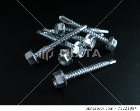 Self-tapping screws galvanized with a semicircular head and a hex head on a black background. Self-tapping screws galvanized with a semicircular head and a hex head on a black background. 73221984