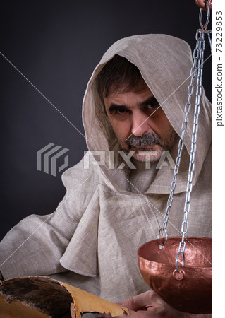 A monk alchemist is engaged in science, writing ancient manuscripts on birch bark 73229853