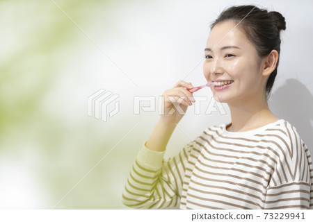 A young woman brushing her teeth A young woman brushing her teeth 73229941