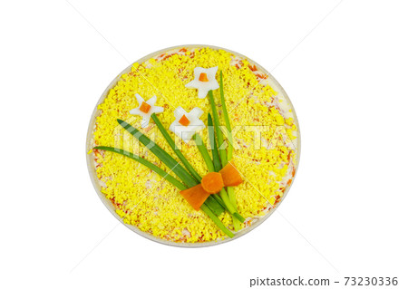 Traditional russian layered salad Mimosa with spring decoration Daffodil isolated on white background. Top view. Decoration is made of egg, green onion and carrot 73230336
