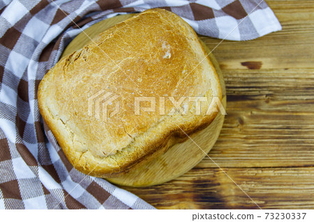 Homemade loaf of bread on a wooden table freshly baked in an electric bread maker. Homemade baking 73230337