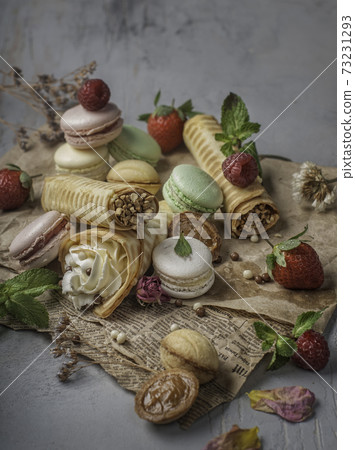 food photography of set different types of desserts side view in a romantic style for a party on a craft paper with berries, flowers and mint close up 73231293