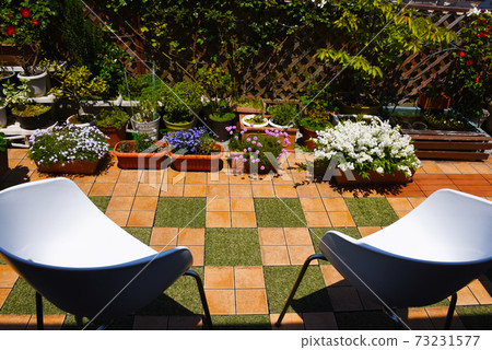 在裝滿鮮花的屋頂陽台上的椅子上放鬆時間 在裝滿鮮花的屋頂陽台上的椅子上放鬆時間 73231577
