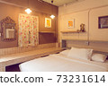 Cozy bedroom interior with a double bed, wooden cabinet, closet and chandelier..Beautiful girls room in white color with carved wood bed..White bedroom with canopy bed and white furniture 73231614