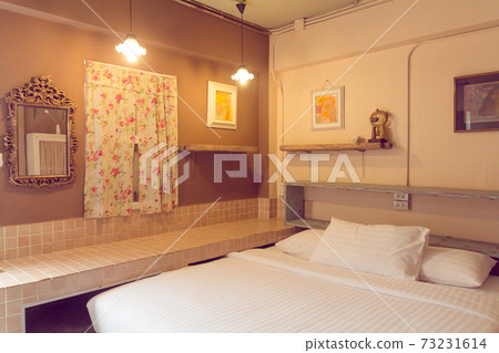 Cozy bedroom interior with a double bed, wooden cabinet, closet and chandelier..Beautiful girls room in white color with carved wood bed..White bedroom with canopy bed and white furniture Cozy bedroom interior with a double bed, wooden cabinet, closet and chandelier..Beautiful girls room in white color with carved wood bed..White bedroom with canopy bed and white furniture 73231614