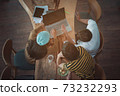 Group of students sitting together with books and laptop..University students doing group study from Top-view..Colleagues coworkers work in coffee cafe.Team group are brainstorming and talking at cafe 73232293