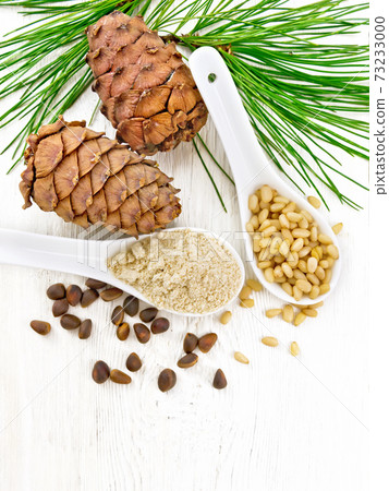 Flour cedar and nuts in two spoons on light board top 73233000