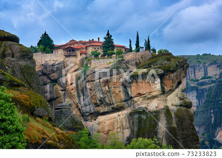 Close view of clifftop Eastern Orthodox monastery of Holy Trinity or Agia Triada in famous Meteora valley, Greece, UNESCO World Heritage, cloudy sky 73233823