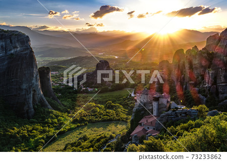 Iconic view of Meteora valley at sunset, mountains, rocks, Moni Agias Varvaras Roussanou nunnery, natural lens flare, Greece, UNESCO World Heritage 73233862