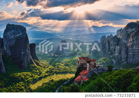Sunset view of nunnery of Moni Agias Varvaras Roussanou and rocks of Meteora, Greece and valley. Cloudy sky, sun rays fall upon. UNESCO World Heritage Sunset view of nunnery of Moni Agias Varvaras Roussanou and rocks of Meteora, Greece and valley. Cloudy sky, sun rays fall upon. UNESCO World Heritage 73233871
