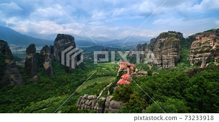 View over nunnery of Moni Agias Varvaras Roussanou and rocks of Meteora, Greece. UNESCO World Heritage. Cloudy sky, sun rays fall on monastery 73233918