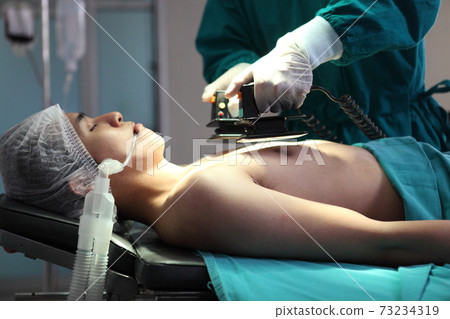 Team of professional surgeons performing operation in hospital , they are holding defibrillator and help while patient will die operation room at hospital Team of professional surgeons performing operation in hospital , they are holding defibrillator and help while patient will die operation room at hospital 73234319