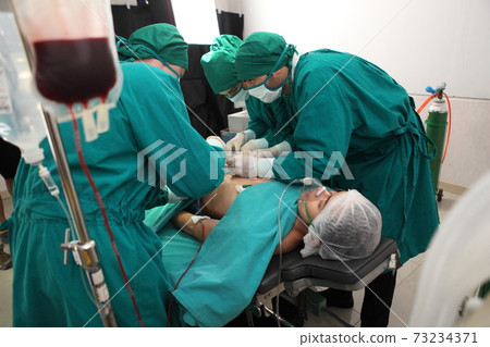 Team of professional surgeons performing operation in hospital operation theater Team of professional surgeons performing operation in hospital operation theater 73234371