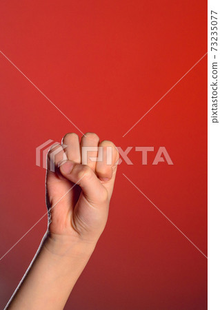 Human hand that squeezed fingers into a fist, symbolizing hatred and resistance, isolated on a red background Human hand that squeezed fingers into a fist, symbolizing hatred and resistance, isolated on a red background 73235077