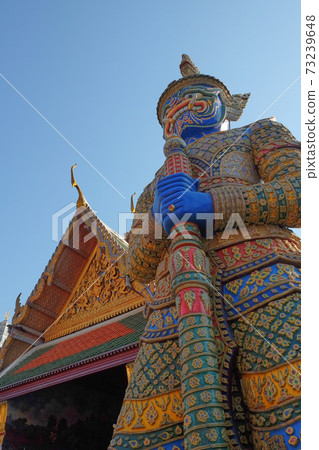 Patterned sculpture of a demonic warrior near a Buddhist temple. 73239648