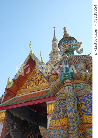 Patterned sculpture of a demonic warrior near a Buddhist temple. 73239654
